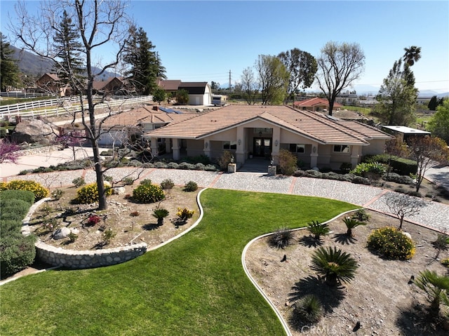 rear view of house featuring stucco siding, a tile roof, a yard, and fence