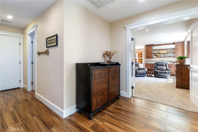 corridor with visible vents, baseboards, and wood finished floors