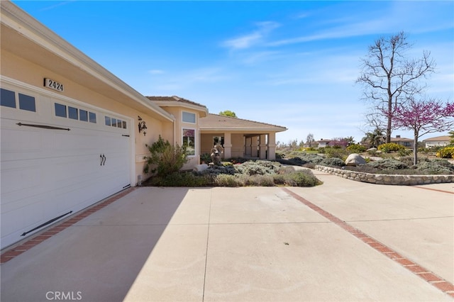 view of front of property featuring stucco siding, driveway, an attached garage, and a tiled roof