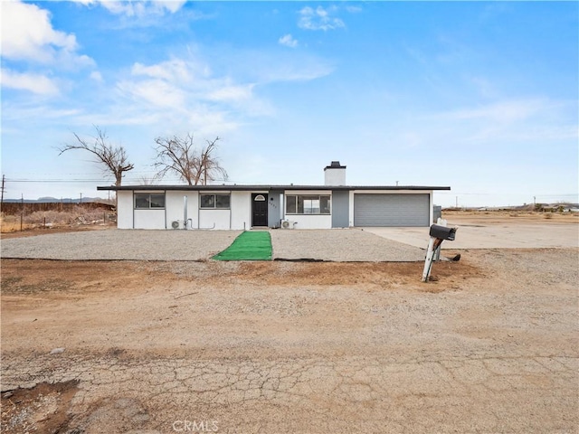 view of front of property with stucco siding, an attached garage, driveway, and a chimney