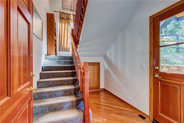 staircase with wood finished floors, visible vents, and baseboards