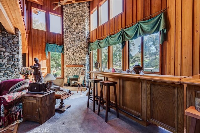 interior space with wooden walls, carpet floors, and ceiling fan
