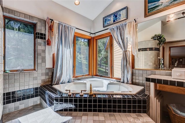full bathroom with a bath, lofted ceiling, tile patterned flooring, and vanity