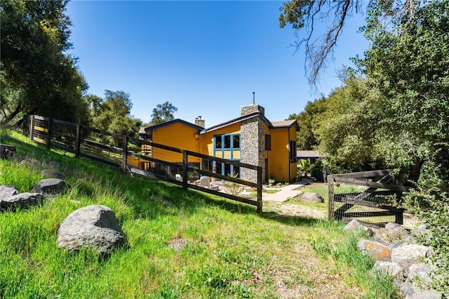 rear view of house with a chimney and fence