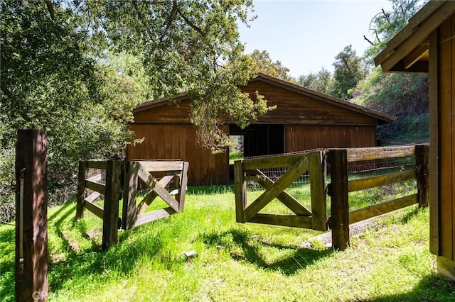view of gate featuring fence and an outbuilding