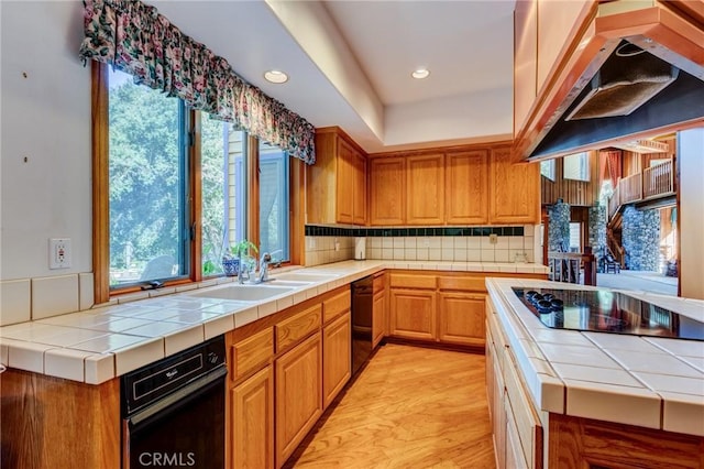 kitchen featuring black appliances, decorative backsplash, tile counters, and exhaust hood