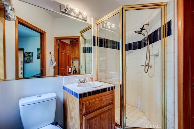 bathroom with a shower stall, toilet, and vanity