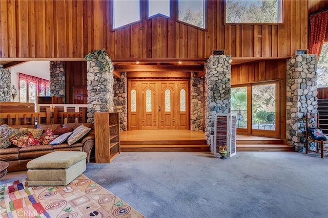 carpeted living room featuring wood walls and a towering ceiling