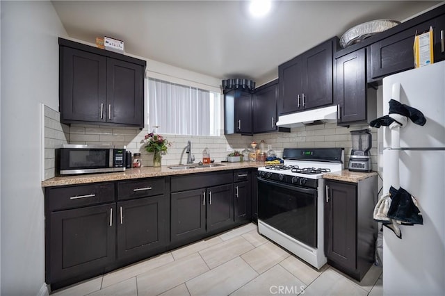 kitchen with range with gas stovetop, freestanding refrigerator, a sink, under cabinet range hood, and stainless steel microwave