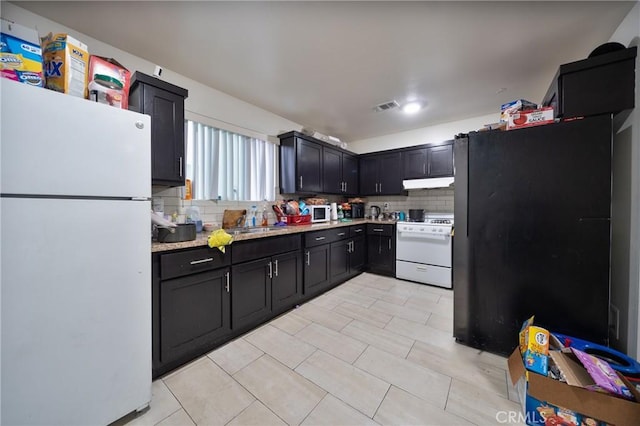 kitchen with decorative backsplash, white appliances, visible vents, and under cabinet range hood