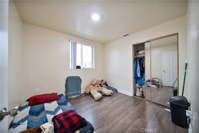 bedroom with a closet, baseboards, visible vents, and wood finished floors