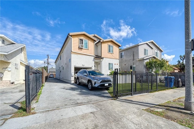 view of front of property featuring a fenced front yard, a residential view, a garage, and driveway