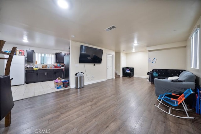 living area with visible vents, baseboards, and light wood-style flooring