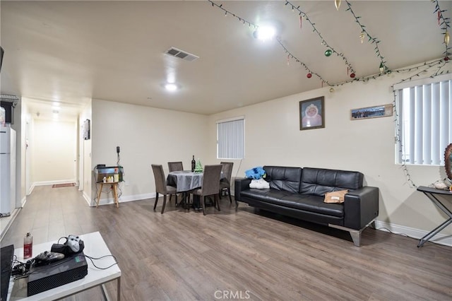 living area featuring visible vents, baseboards, and wood finished floors