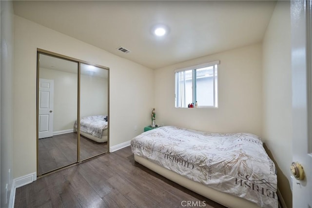 bedroom with visible vents, baseboards, a closet, and wood finished floors