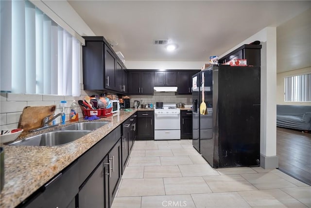 kitchen featuring visible vents, a sink, decorative backsplash, white gas range oven, and under cabinet range hood