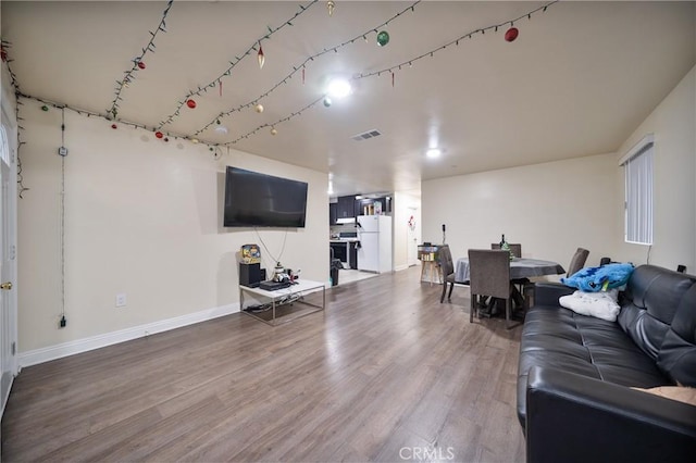 living area with visible vents, baseboards, and wood finished floors