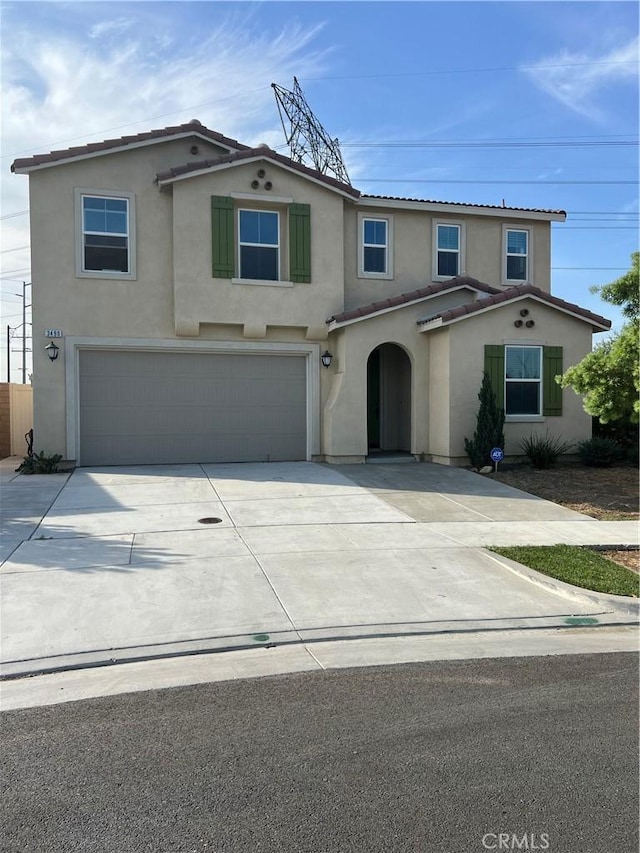 traditional-style house featuring a tiled roof, an attached garage, driveway, and stucco siding