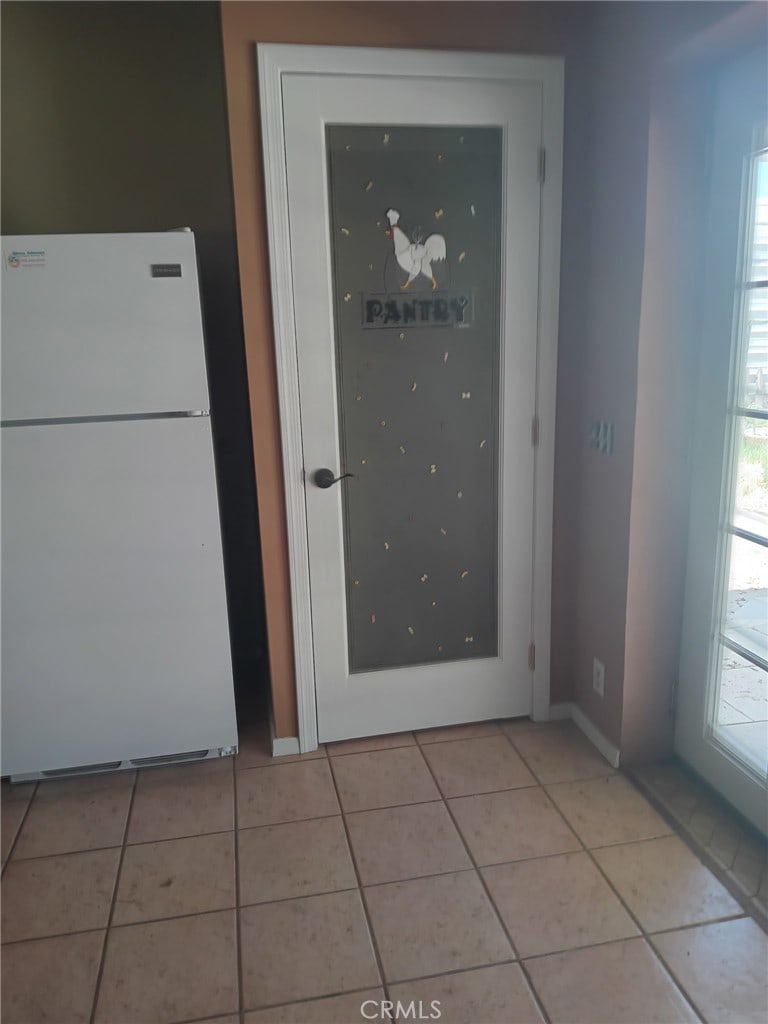 kitchen with light tile patterned floors, baseboards, and freestanding refrigerator