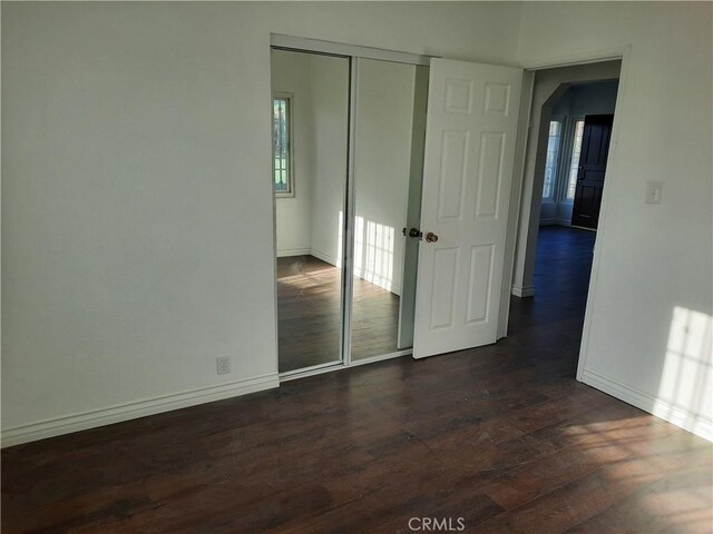 10701 Doty Ave, Inglewood, CA 90303 - unfurnished bedroom with dark wood finished floors, arched walkways, a closet, and baseboards