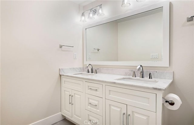 bathroom with a sink, baseboards, and double vanity