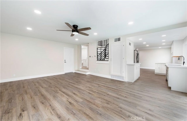 unfurnished living room with visible vents, a ceiling fan, recessed lighting, stairway, and light wood finished floors