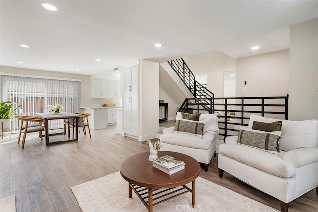 living area with recessed lighting, stairway, baseboards, and light wood-style flooring