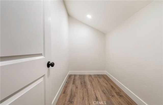 interior space with vaulted ceiling, wood finished floors, and baseboards