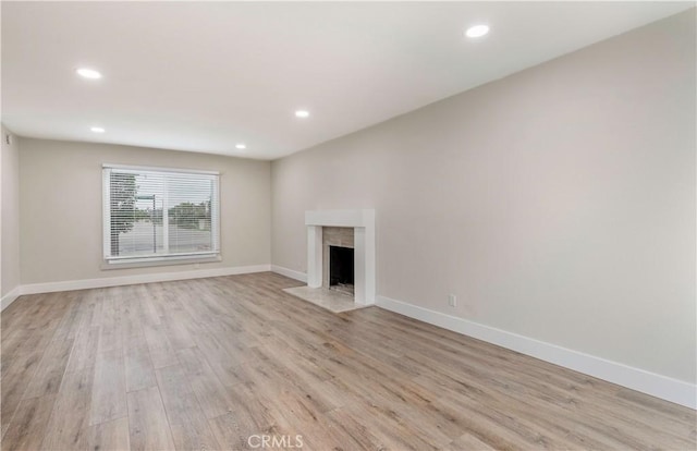 unfurnished living room with recessed lighting, baseboards, and light wood-style floors