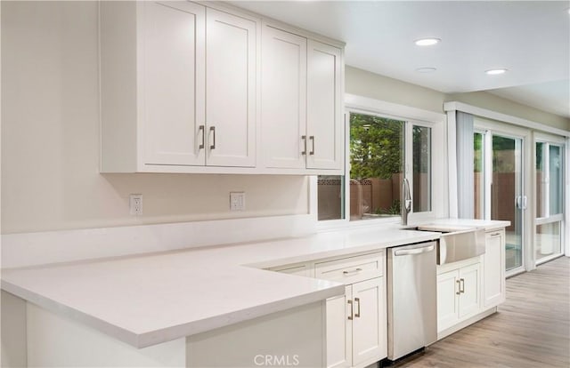 kitchen with light wood-style flooring, a sink, white cabinetry, light countertops, and dishwasher