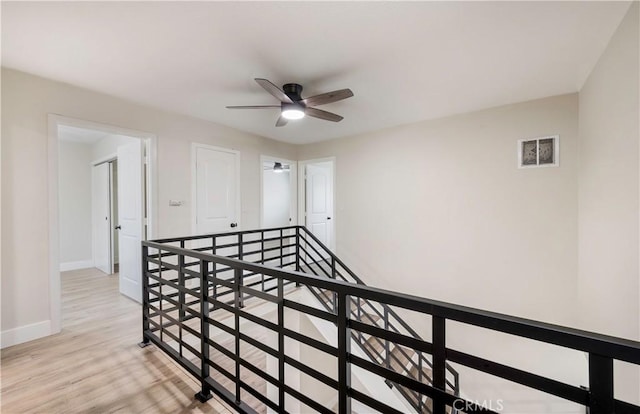 interior space with light wood-type flooring, baseboards, an upstairs landing, and visible vents