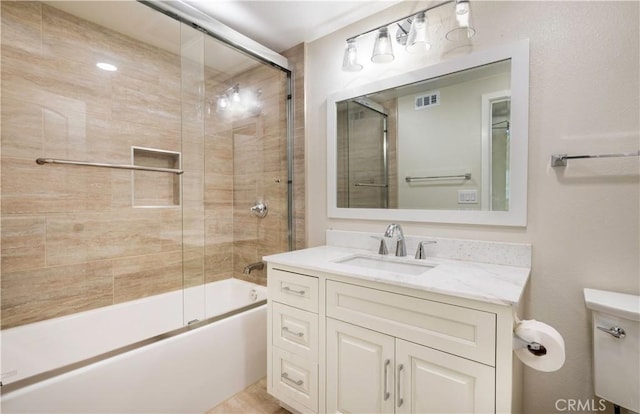 full bathroom with visible vents, vanity, toilet, and bath / shower combo with glass door