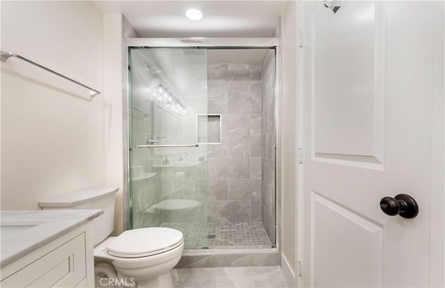 full bathroom featuring a stall shower, toilet, and vanity