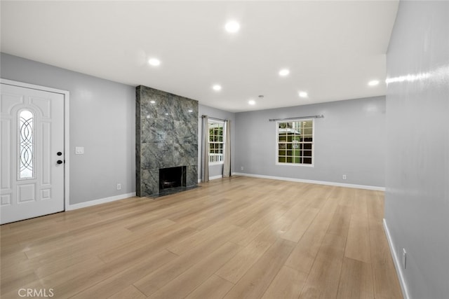 unfurnished living room with recessed lighting, baseboards, light wood-style floors, and a premium fireplace