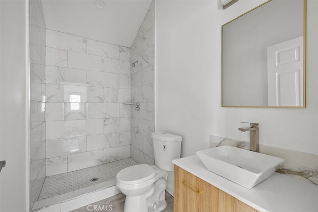 full bathroom featuring toilet, vanity, and a tile shower