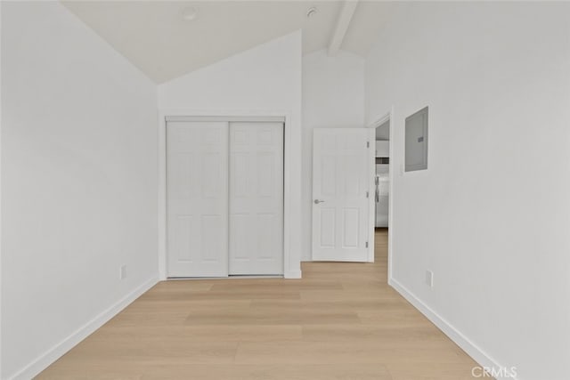 unfurnished bedroom with electric panel, a closet, light wood finished floors, baseboards, and vaulted ceiling with beams