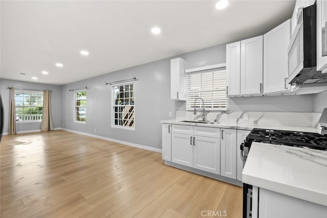 kitchen with baseboards, recessed lighting, a sink, white cabinets, and light wood-type flooring