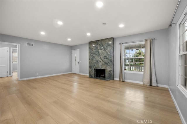 unfurnished living room featuring visible vents, recessed lighting, a tile fireplace, and light wood-style floors