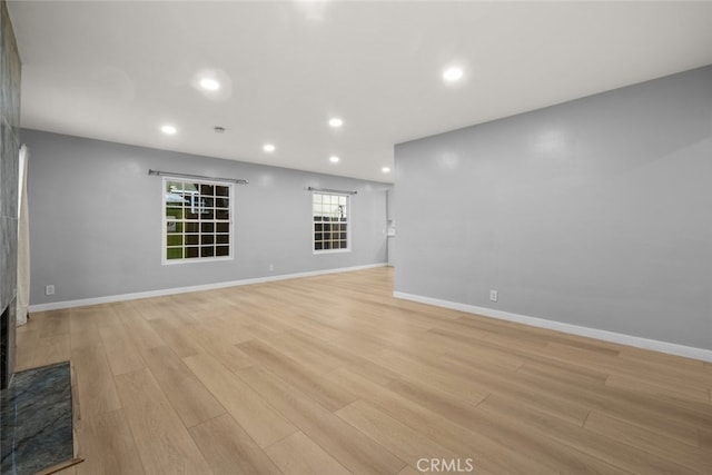 unfurnished living room featuring recessed lighting, baseboards, and light wood-style flooring