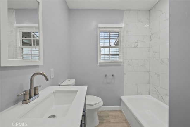 bathroom featuring vanity, toilet, wood finished floors, and baseboards