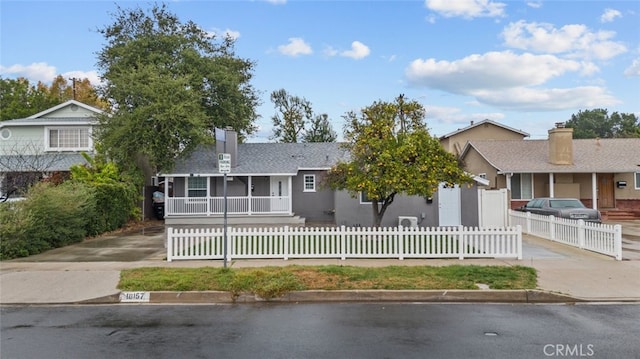 ranch-style home with a fenced front yard, a shingled roof, a chimney, and stucco siding