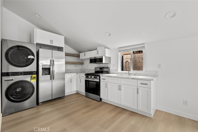 kitchen with light wood-type flooring, light countertops, stacked washer and clothes dryer, stainless steel appliances, and a sink