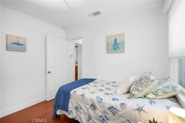 bedroom with visible vents, ornamental molding, baseboards, and wood finished floors