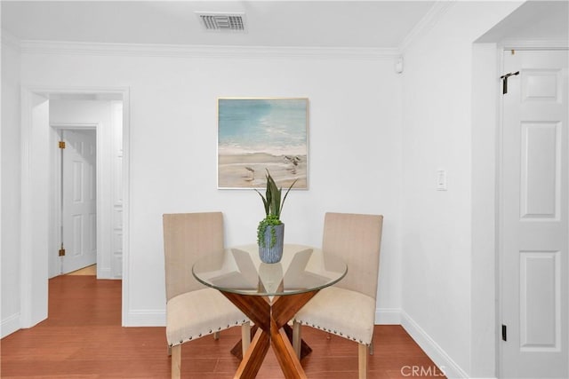 dining space featuring crown molding, wood finished floors, visible vents, and baseboards