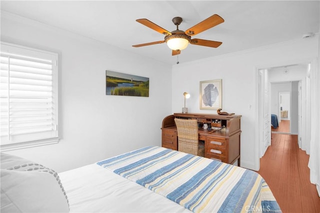 bedroom with baseboards, crown molding, ceiling fan, and wood finished floors