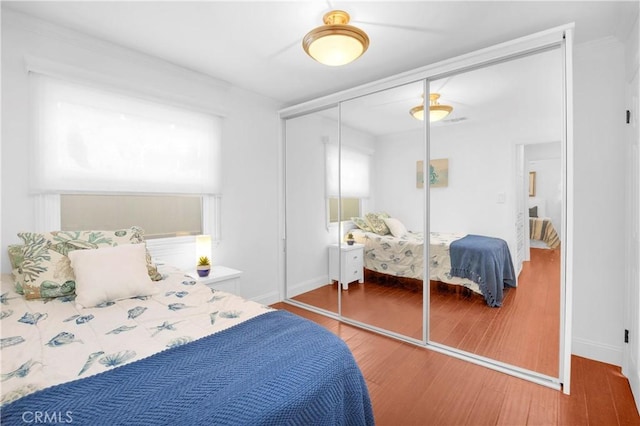 bedroom with a closet, baseboards, and wood finished floors