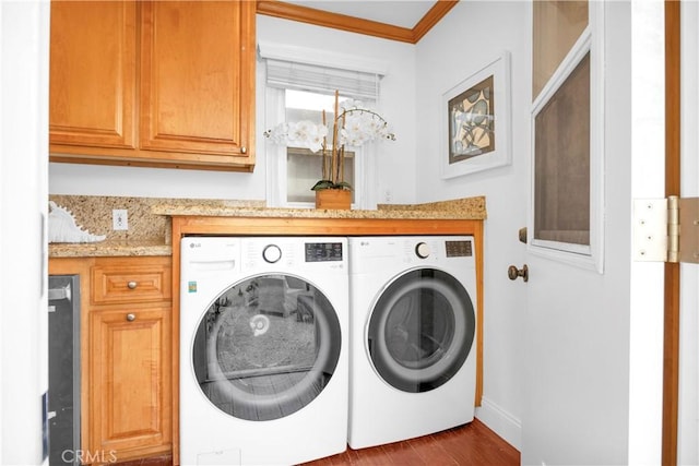 laundry room featuring washer and clothes dryer, cabinet space, dark wood finished floors, and crown molding