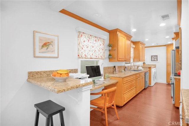 kitchen featuring visible vents, a sink, appliances with stainless steel finishes, a kitchen breakfast bar, and light wood-type flooring