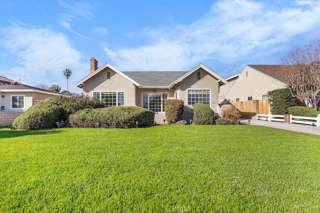 ranch-style home featuring stucco siding, a chimney, a front yard, and fence