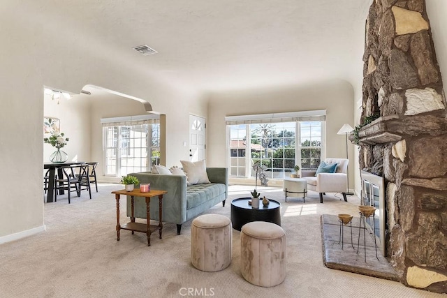 living room with a wealth of natural light, visible vents, a fireplace, and carpet